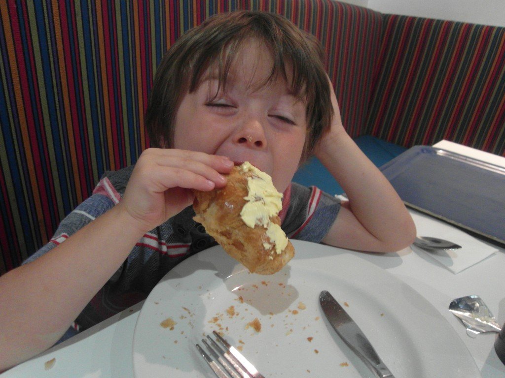 Boy eating a croissant with butter