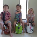 Three children sitting on their Trunki suitcases